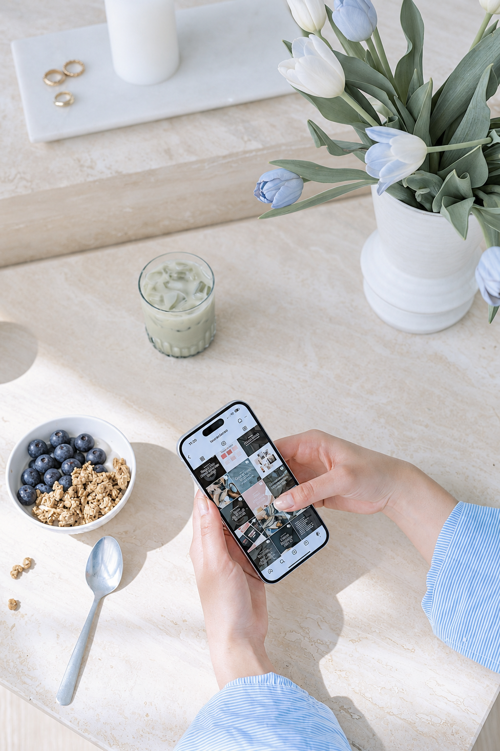 Woman viewing a social media profile on her phone beside blueberries and pale blue flowers.