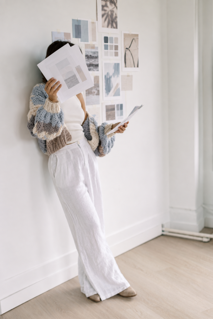 Woman in a powder-blue and white striped shirt using a tablet beside an iced coffee on a white desk.